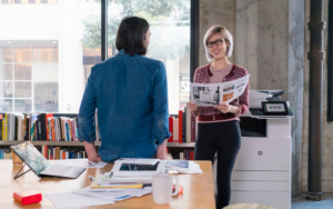 Two Coworkers Are Jolly Standing Next To Hp Printer In Office