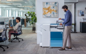 Man Using Colorful Hp Printer In Modern Office With People Working