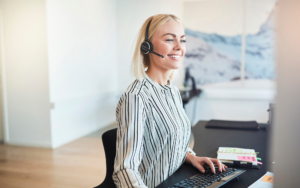 Smiling Businesswoman Talking On A Headset At Her Office Desk