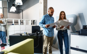 Two Employees Using New Modern Printer In Office