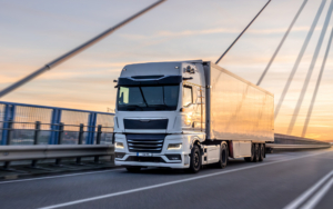 White Truck Crossing Bridge At Sunset. Urban Logistics In Motion
