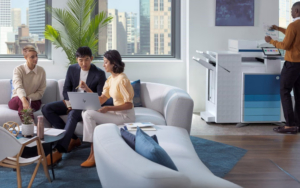 Hp Branded Image Of A Group Of People In Modern Office Conversing And A Man Standing By Printer