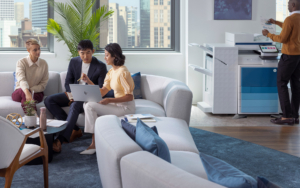 Hp Branded Image Of A Group Of People In Modern Office Conversing And A Man Standing By Printer V2