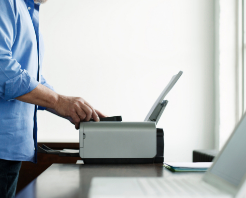 Side View Midsection Of A Mature Man Using Printer At Study Table In House
