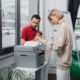 Blonde Woman Copying Document Near African American Manager With Paper Cup